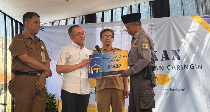 Ketua DPRD Kota Bandung H. Asep Mulyadi, S.H., menyerahkan paket umrah kepada Petugas Satlinmas Kelurahan Caringin, di Kantor Kelurahan Caringin, Kecamatan Bandung Kulon, Senin, 11 Mei 2026.